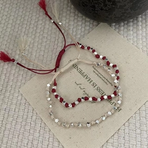 Détail de bracelets tressés en argent S925 rouge et beige sur une pochette en toile