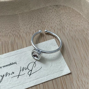 Detail of S925 silver geometric ring with dark red stone on minimalist wooden tray