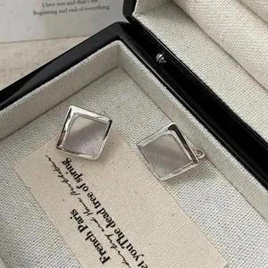 Makroaufnahme geometrischer quadratischer Silber-Ohrstecker mit gebürsteter Textur auf Box