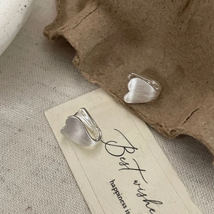 Macro detail of silver S925 heart earrings featuring a unique brushed metal texture
