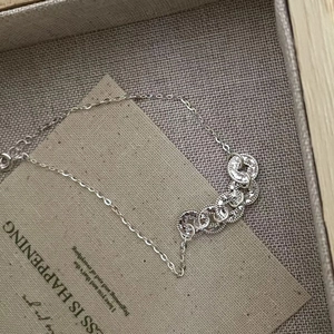 Macro shot of silver chain bracelet with five woven textured rings on a grey display box