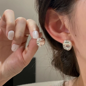 Macro shot of S925 sterling silver irregular glossy stud earrings worn on a female ear