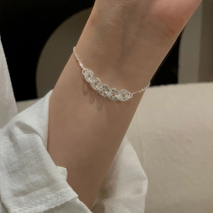 Detail of S925 silver faceted coin link bracelet worn on wrist with linen sleeve