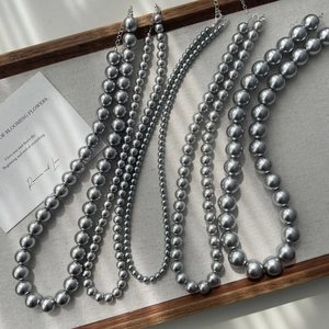 Elegant multi-layered gray imitation pearl necklaces in various sizes on a wooden tray