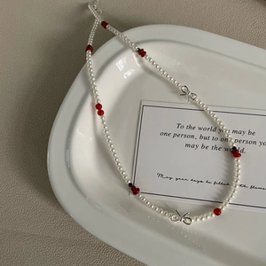 Détail du collier avec nœud en argent S925, perles blanches et perles rouges en plateau