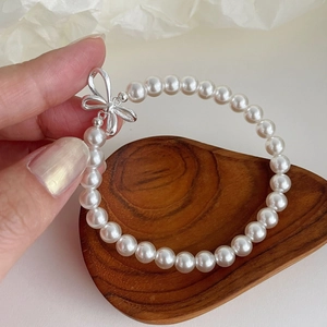 Sweet S925 silver pearl bracelet with a bow charm displayed on a wooden tray