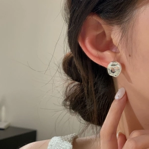 Close-up of minimalist irregular liquid-style S925 sterling silver studs worn by a model