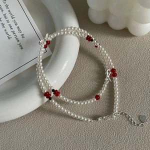 Détail du pendentif nœud en argent S925 et collier de perles double avec perles rouges
