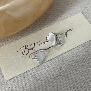 Macro detail of S925 sterling silver heart earrings with brushed matte finish texture