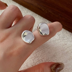 Detailed view of silver irregular liquid metal studs with reflective mirror finish