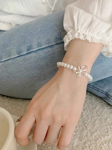 Close-up of S925 silver bow pendant and round white pearls on a princess style bracelet