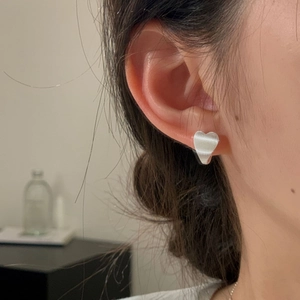 Close-up of minimalist S925 sterling silver heart stud earring with a brushed texture