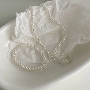 Detailed view of white pearl jewelry set featuring silver bow accents and glossy finish