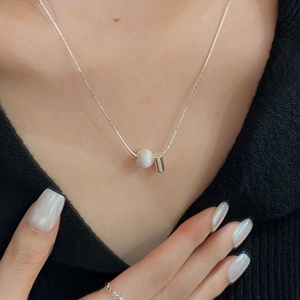 Détail macro du collier avec pendentif boule brossée en argent S925 sur la clavicule