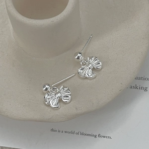 Detailed view of silver bow-shaped stud earrings with realistic ribbon texture finish