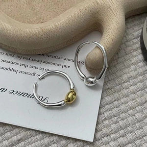 Macro detail of silver and gold plated minimalist open rings with mirror polished finish