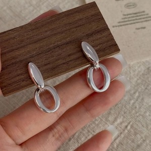 Detailed close-up of S925 sterling silver hollow oval double-hoop earrings on wood