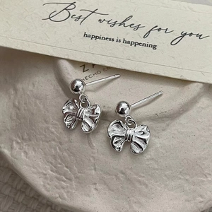 Elegant 925 sterling silver bow knot stud earrings on a textured stone surface