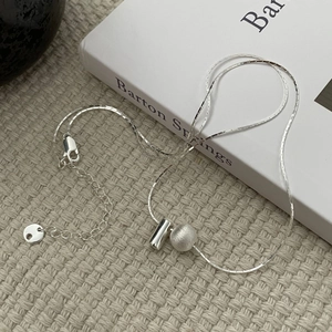 Collier en argent sterling S925 avec pendentif boule brossée sur un livre blanc