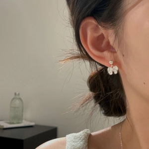 Elegant S925 sterling silver bow knot stud earrings on female model in warm lighting