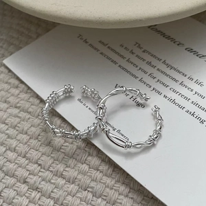 Detailed view of S925 silver layered rings with textured grid and woven rope designs