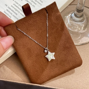 Détail du pendentif étoile en argent S925 avec perle irisée et diamant sur carte foncée