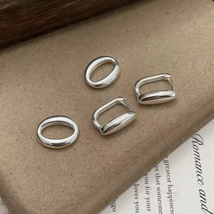 Macro shot of polished S925 sterling silver hollow oval hoops on velvet padding