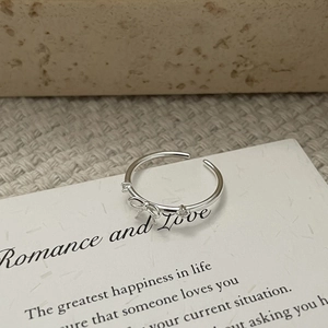 Gros plan d'une bague nœud en argent 925 avec zircons sur pierre naturelle et tissu doux