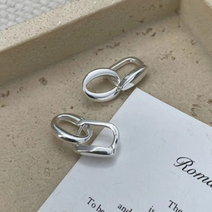 Macro shot of S925 sterling silver geometric oval earrings on a beige stone tray