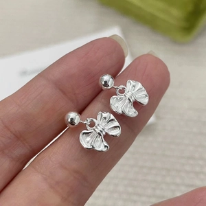 Macro shot of silver bow earrings featuring polished ball studs and silk texture detail