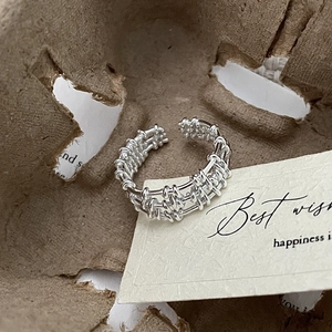 Macro detail of S925 sterling silver multilayer ring with woven lattice texture on paper