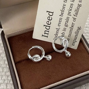 Macro shot of S925 sterling silver twisted hoop earrings with ball pendants on velvet