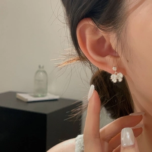 Detail of silver bow stud earring in 925 sterling silver worn by a model in soft light