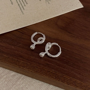 Macro shot of S925 sterling silver twisted hoop earrings on a rustic wood background