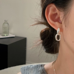 Macro side view of silver dual-link oval earrings worn on model for a minimalist style