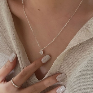 Close-up of a minimalist S925 sterling silver zircon necklace and rope ring on a model