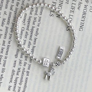Macro shot of silver beaded bracelet featuring mahjong and horse charms on book page