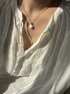 Gros plan d'un collier étoile en perle baroque porté par une femme pour un style minimaliste