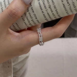 Macro view of double-layered silver grid ring worn on finger with minimalist design