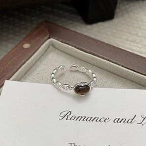 Close-up of S925 silver pig nose ring with brown chalcedony stone in a wooden tray