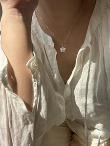 Gros plan du collier étoile en nacre et argent S925 porté par un mannequin au soleil