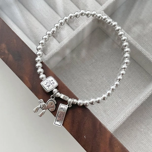 Detailed shot of S925 silver beaded bracelet with horse and wealth charm on wooden surface