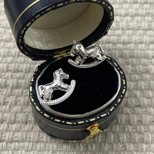 Close-up of S925 sterling silver rocking horse studs in a blue velvet jewelry box