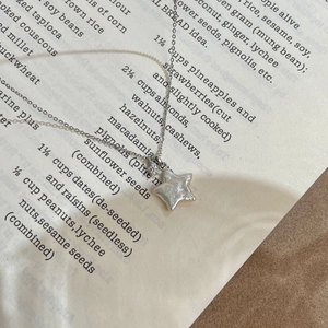 Gros plan du pendentif étoile en argent S925 avec nacre sur les pages d'un livre
