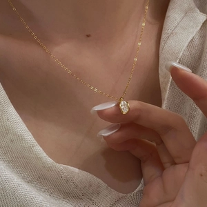 Elegant gold necklace with oval zircon pendant worn by model for minimalist daily style