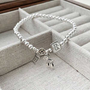 Detail of S925 silver beaded bracelet featuring lucky coin and money horse charms