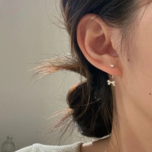 Detailed close-up of S925 silver bow stud earrings with zircon stones on female ear