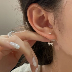 Close-up of S925 silver bow drop earring with polished metallic ball stud on model