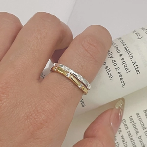 Close-up of stacked S925 silver and gold minimalist rings featuring small zircon stones