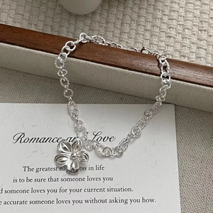 Detailed close-up of 925 sterling silver flower pendant on a twist link chain bracelet